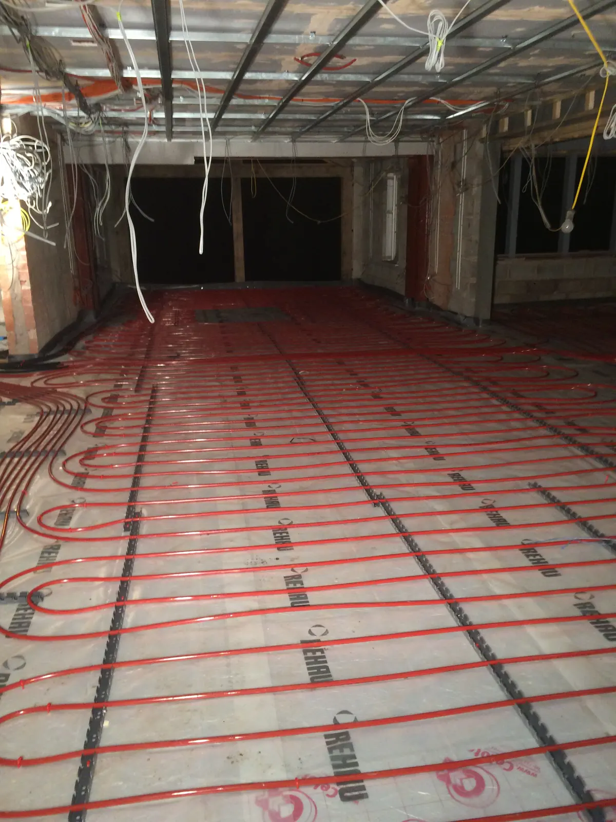 Underfloor heating pipe laid across insulation on a large open-plan floor