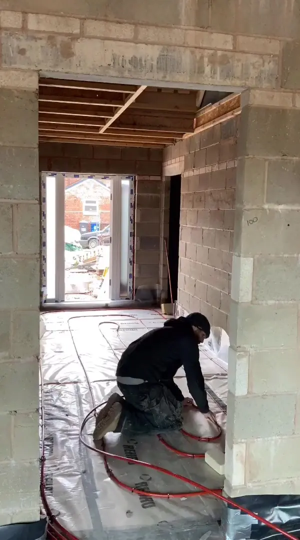 Callum kneeling to fix underfloor heating pipe onto insulation on a new extension